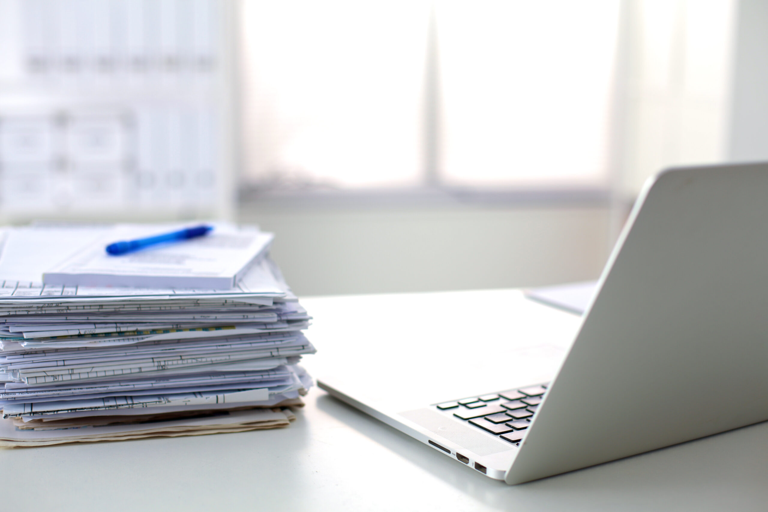 Laptop with stack of folders on table on white background